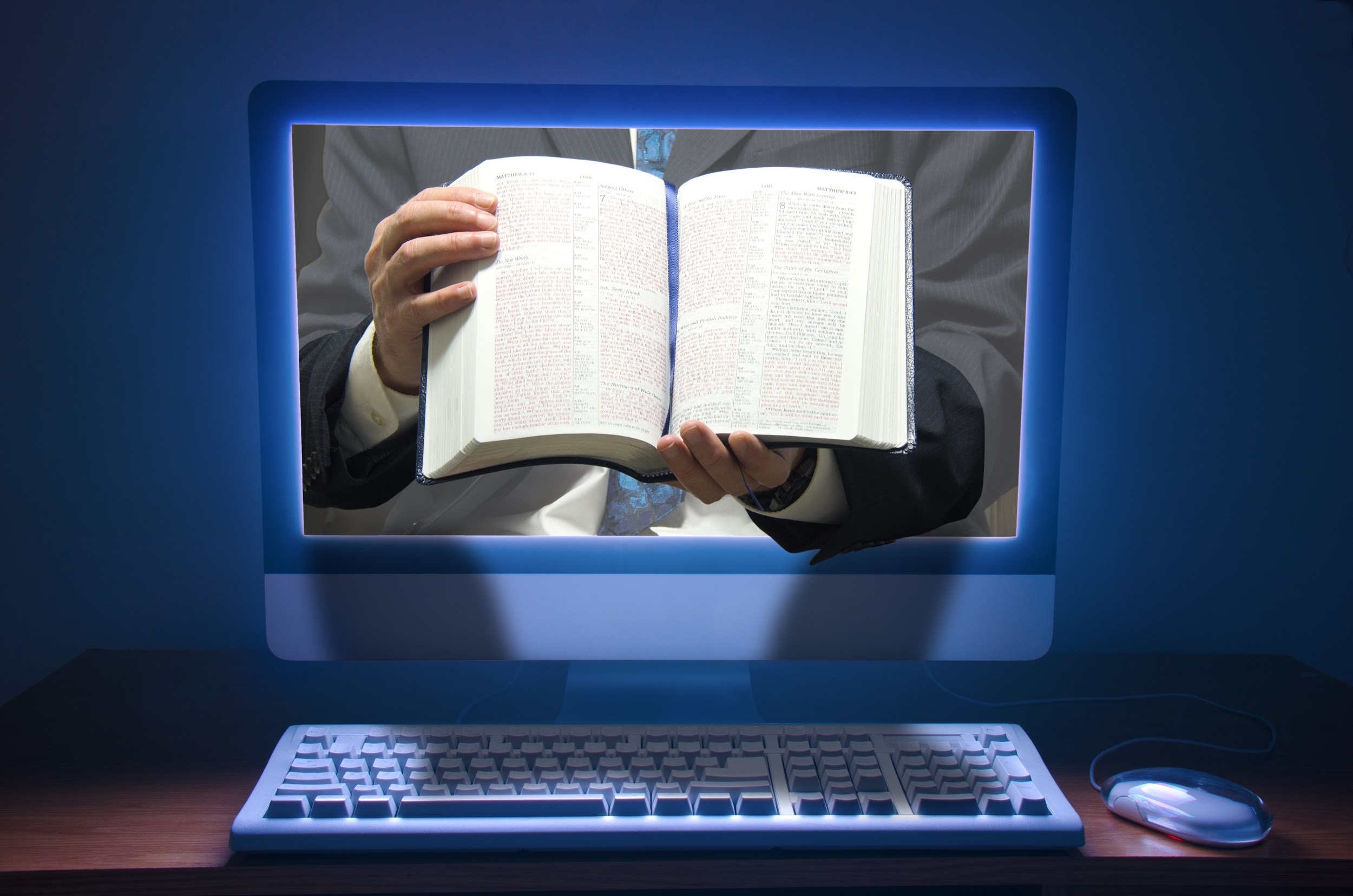 computer with a man showing a bible through the screen