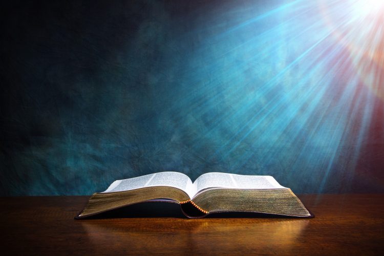 open bible on wood table with light coming from above