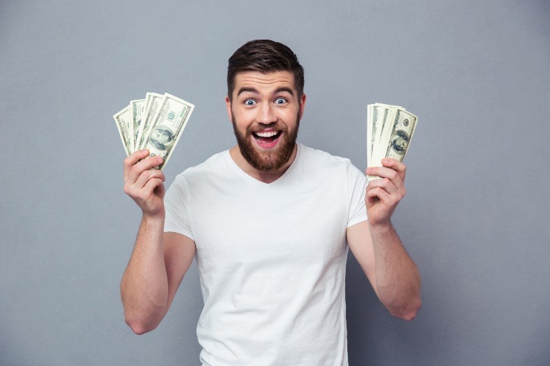 man smiling and holding up cash