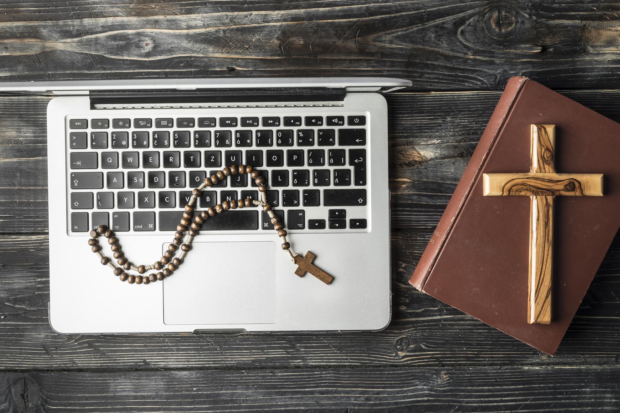 bible and laptop with cross necklace sitting on a desk
